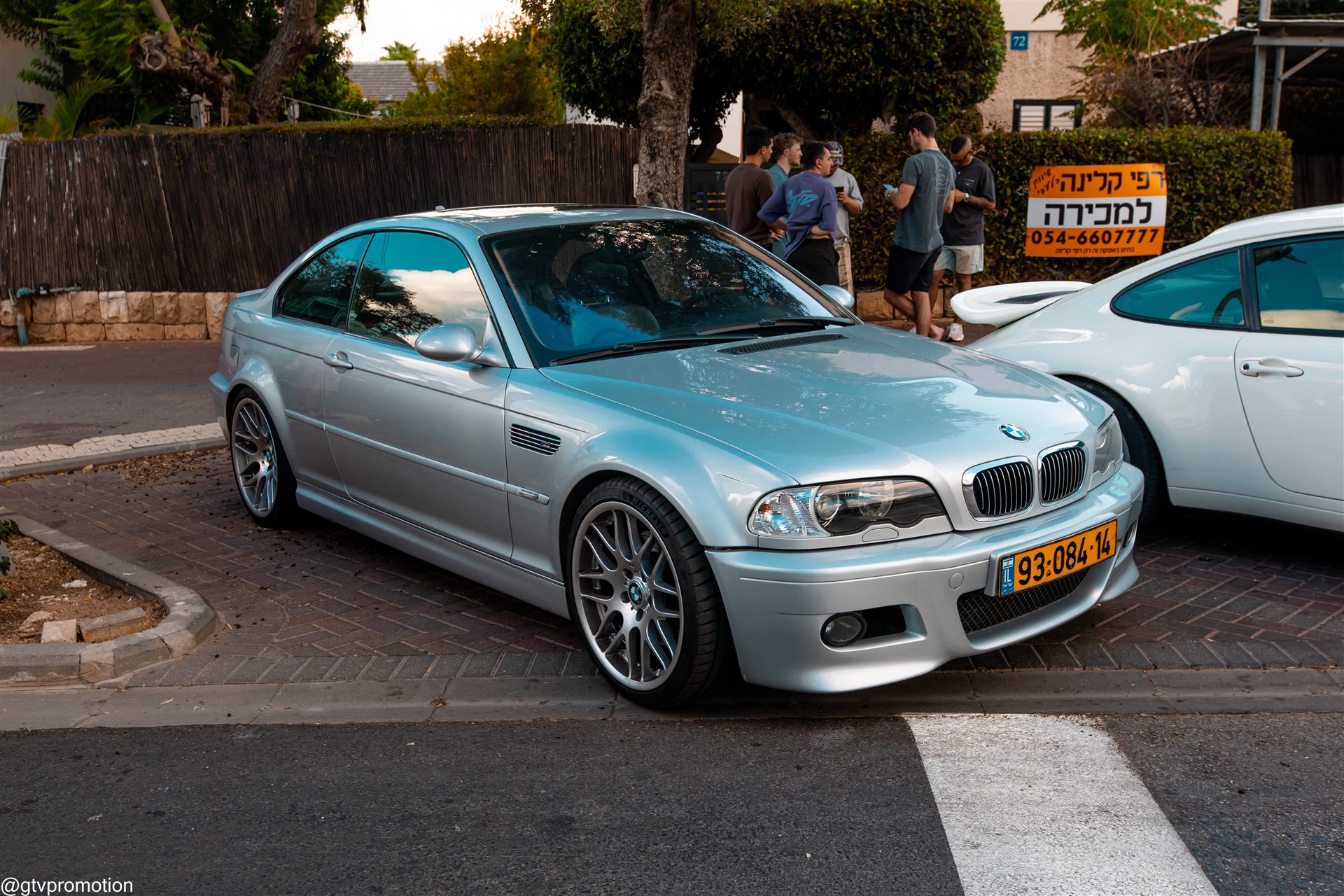 BMW M3 E46 כסופה במבט קדמי אלכסוני לצד מכונית ספורט לבנה במפגש צהלה