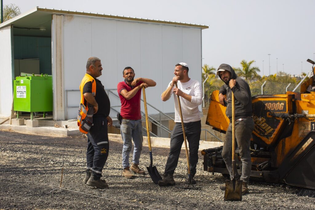 צוות העובדים של אריאל סחר לצד מכונת הסלילה וכלי העבודה